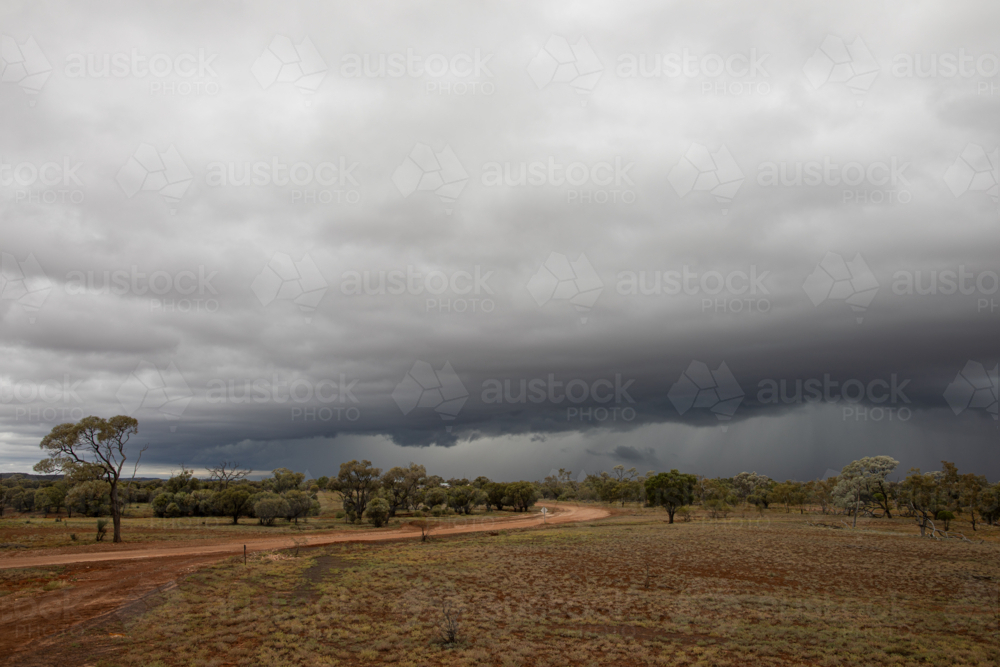 Storm front rolling past over a gravel road - Australian Stock Image