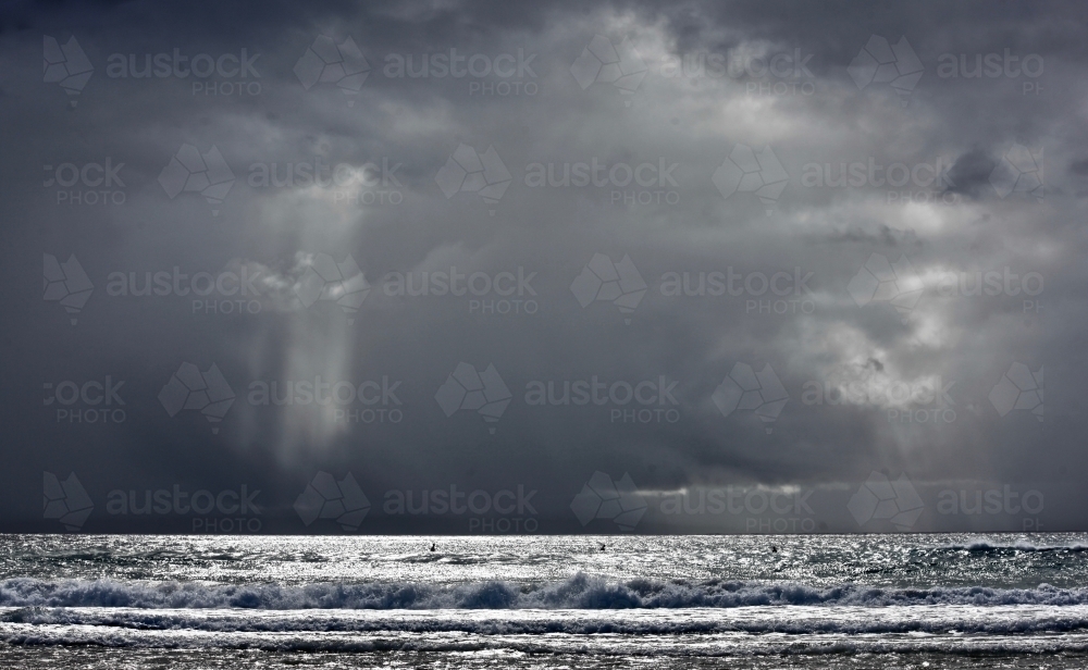 Storm over ocean, casting light, silver sea, moody - Australian Stock Image