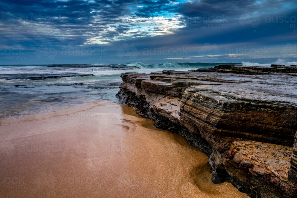 Stormy clouds over a rock shelf at Turimetta Beach - Australian Stock Image