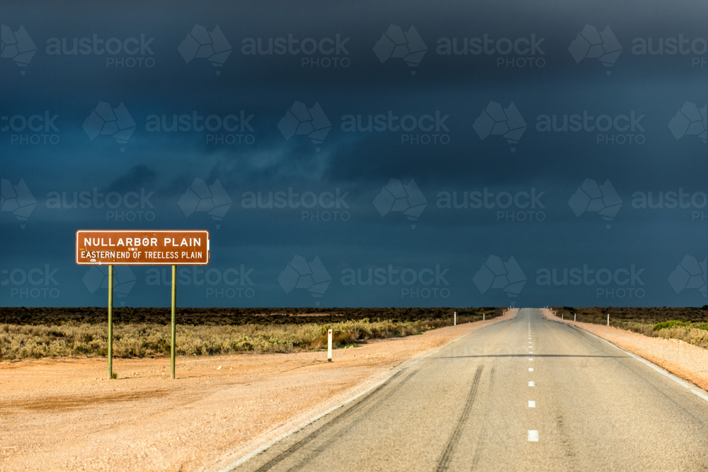 Straight road leading into the Nullarbor Plain under moody sky. - Australian Stock Image