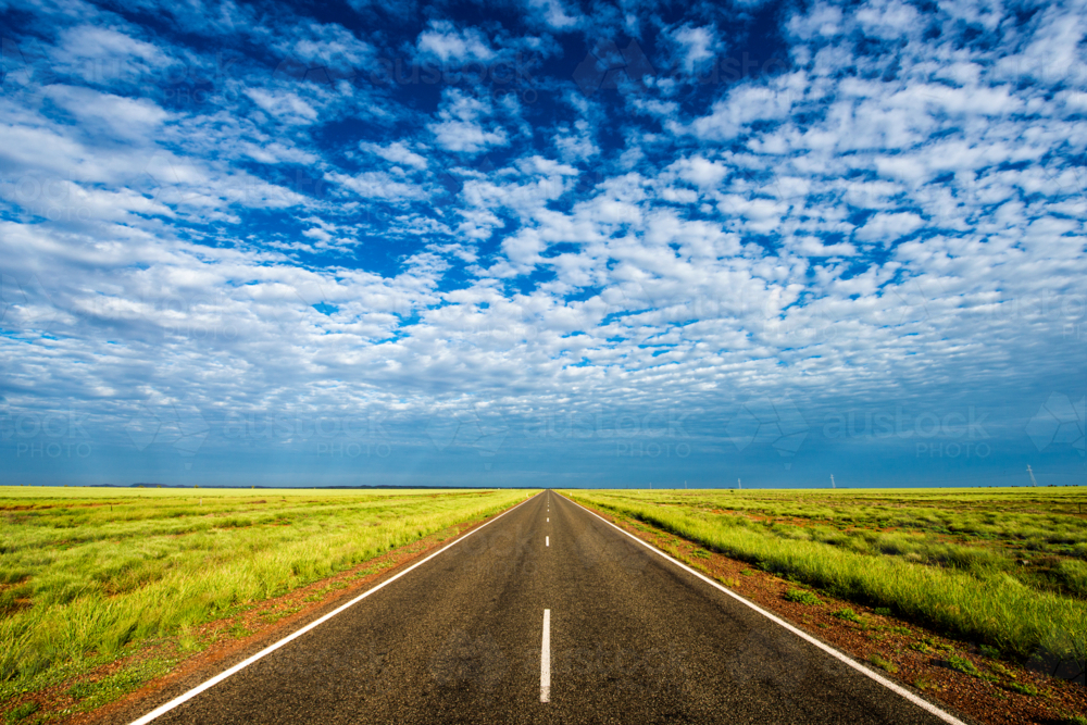 Straight rural road vanishing into distant horizon under blue sky - Australian Stock Image