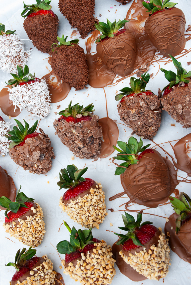 Strawberries coated in chocolate, coconut and nuts on a plate - Australian Stock Image