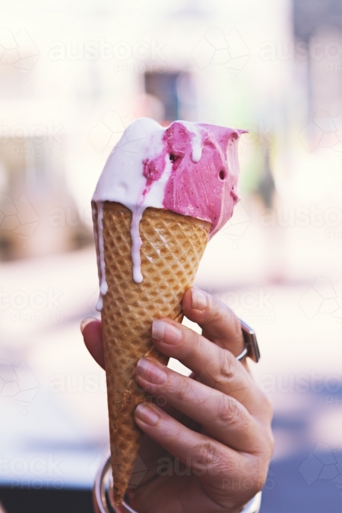 Strawberry and vanilla ice cream cone melting and dripping - Australian Stock Image