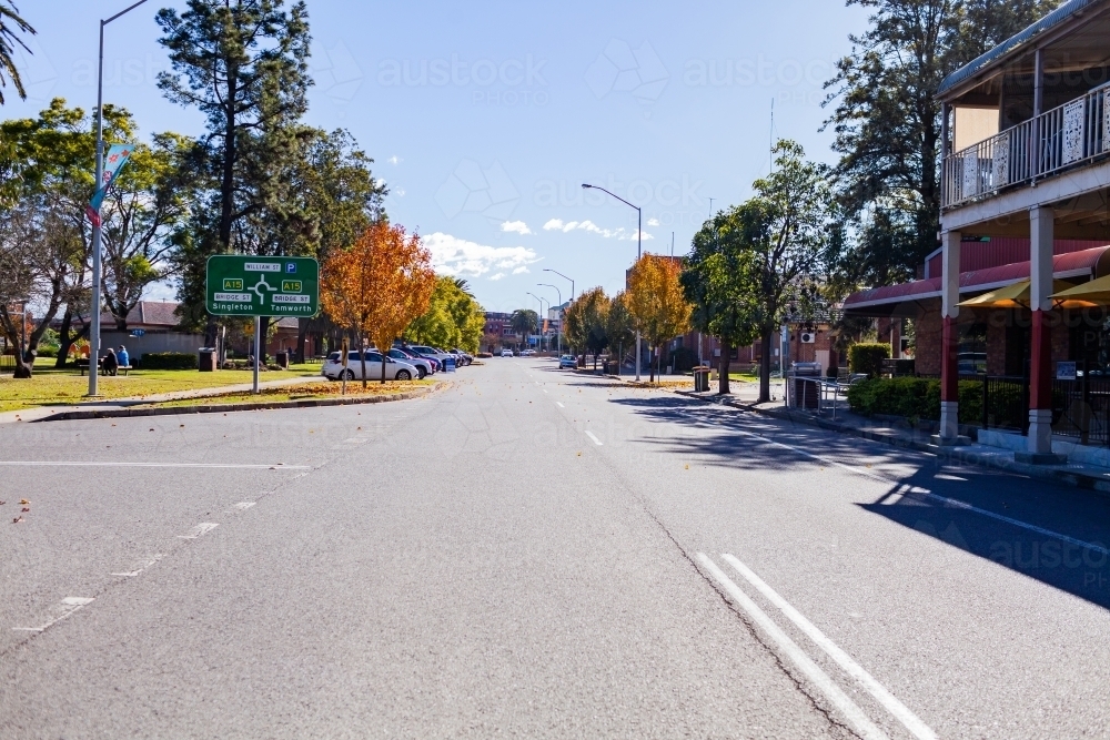 Image of Street in Muswellbrook, NSW in autumn with cars parked beside park and sign Austockphoto