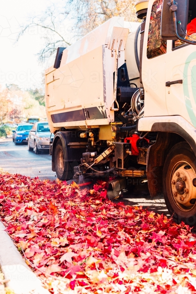 Image of street sweeper clearing autumn leaves on the side of a road ...