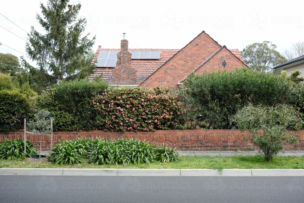Street view of an old brick house surrounded by garden - Australian Stock Image