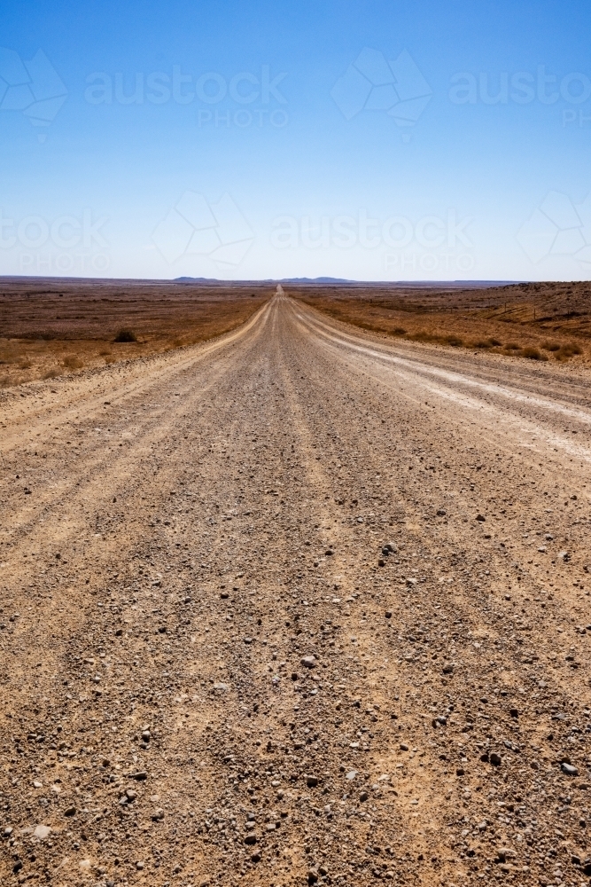 stretch of dirt road in desert landscape, vertical - Australian Stock Image