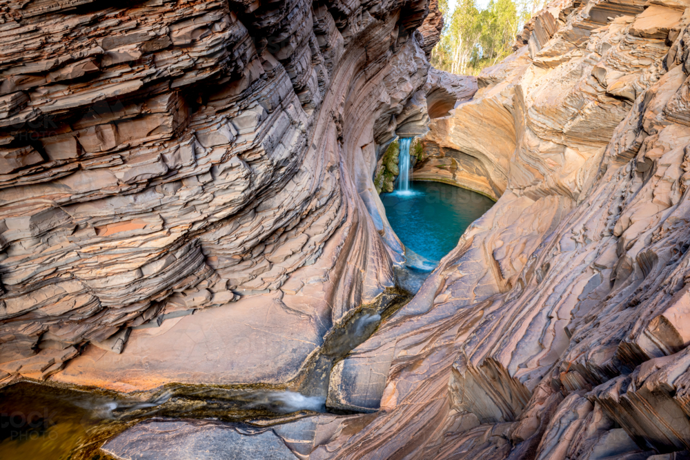 Striking rock layers lead into a turquoise pool beneath soft morning light. - Australian Stock Image