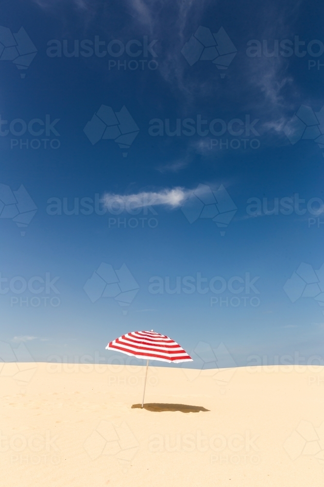 Stripy umbrella on a beach - Australian Stock Image