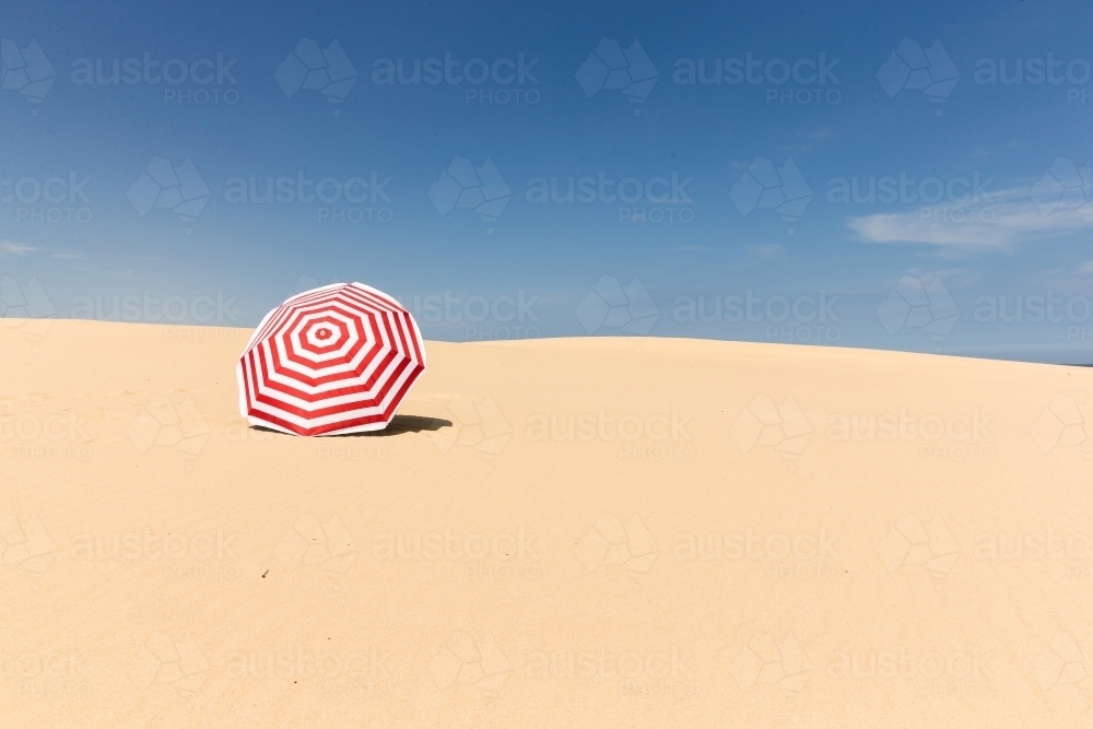 Stripy umbrella on a sand dune - Australian Stock Image