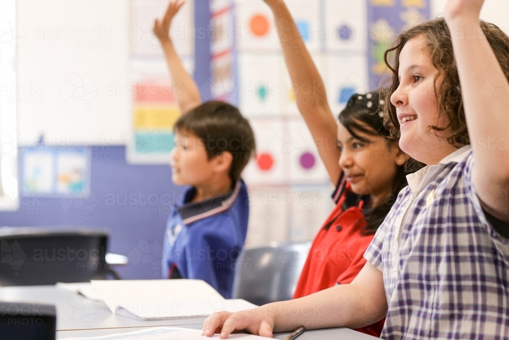 Students raising their hands to answer a question - Australian Stock Image