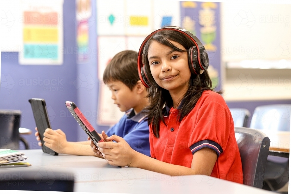 Students with headphones and digital devices in the classroom - Australian Stock Image