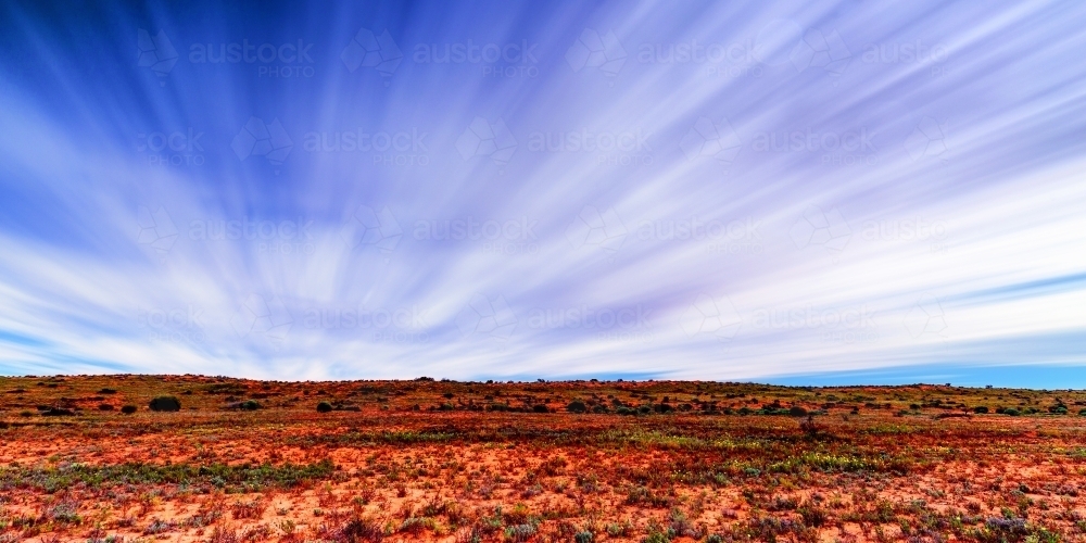 Stunning blue and white streaky sky over red plains - Australian Stock Image