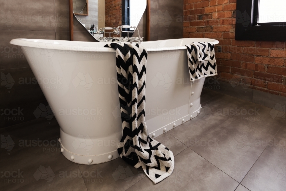 Styled bath towel draped over a freestanding vintage style bath tub - Australian Stock Image