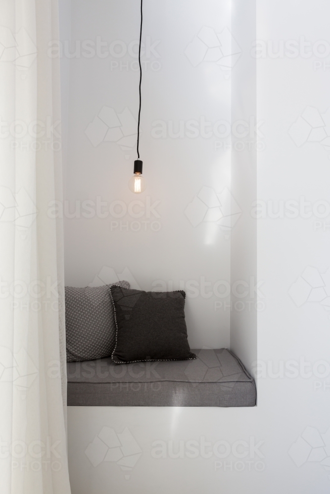 Styled reading nook with grey cushions and single pendant light - Australian Stock Image
