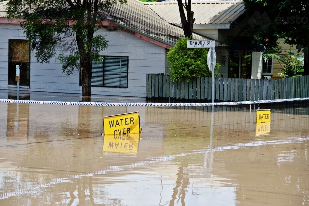 Submerged flood sign reading "water over road" - Australian Stock Image