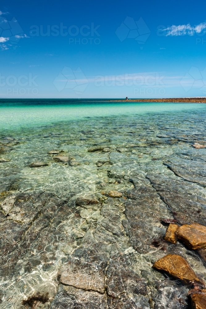 submerged rocks under clear water and blue sky - Australian Stock Image