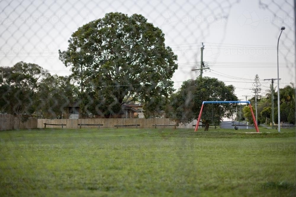 Suburban playground in park through wire fence - Australian Stock Image