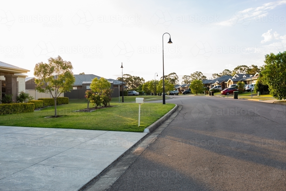 Suburban street with curved lamp post in late afternoon light - Australian Stock Image