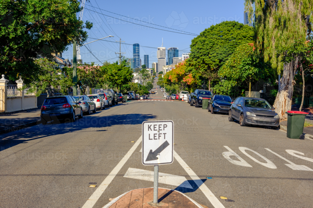 Suburban Street with Keep Left Sign and Brisbane CBD in the Background - Australian Stock Image