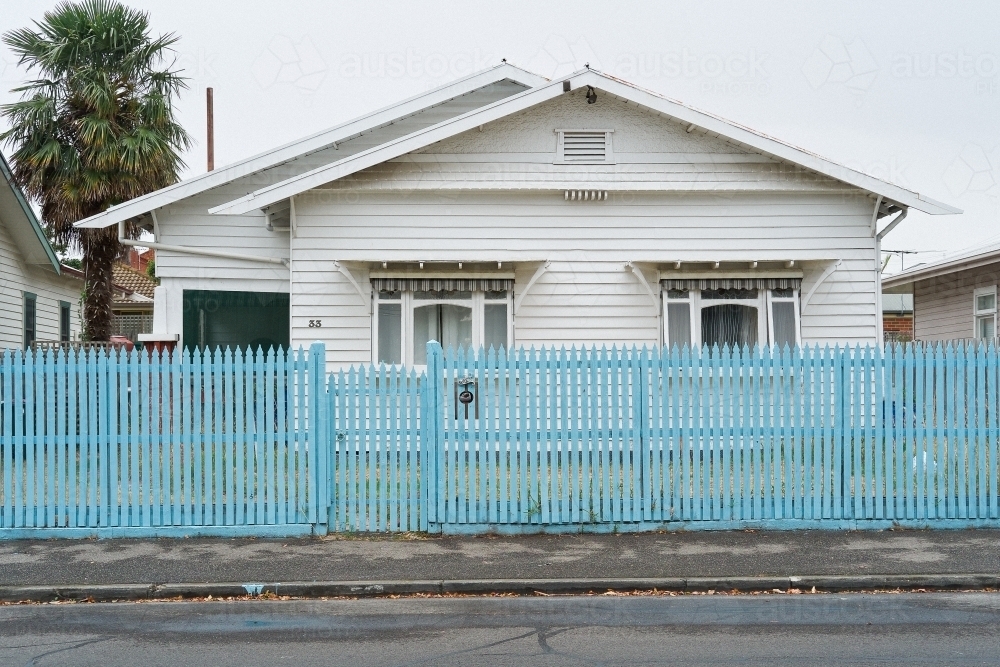 Suburban weatherboard house behind blue picket fence - Australian Stock Image