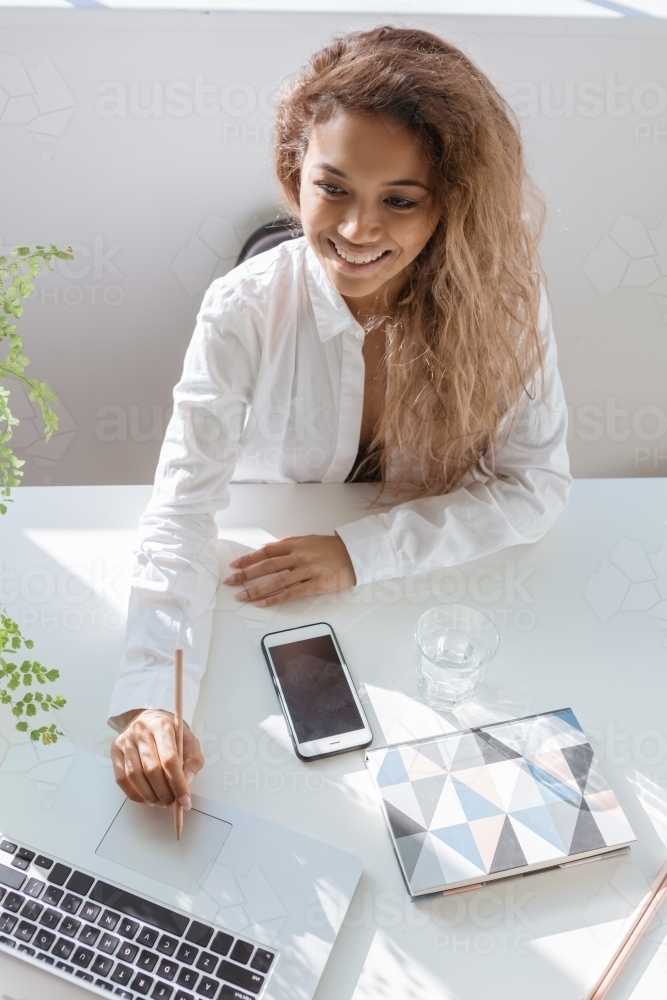 Successful blogger working on her laptop from above - Australian Stock Image