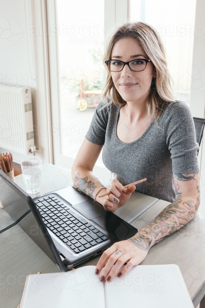 Successful business woman working at home with reading glasses - Australian Stock Image