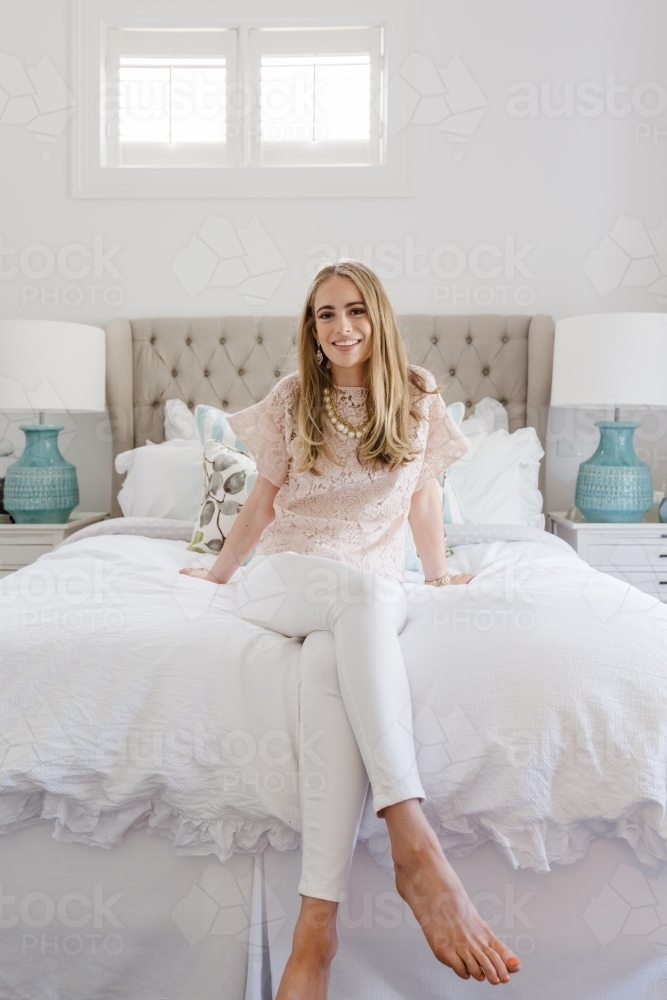 Successful young blonde woman in her bedroom smiling - Australian Stock Image