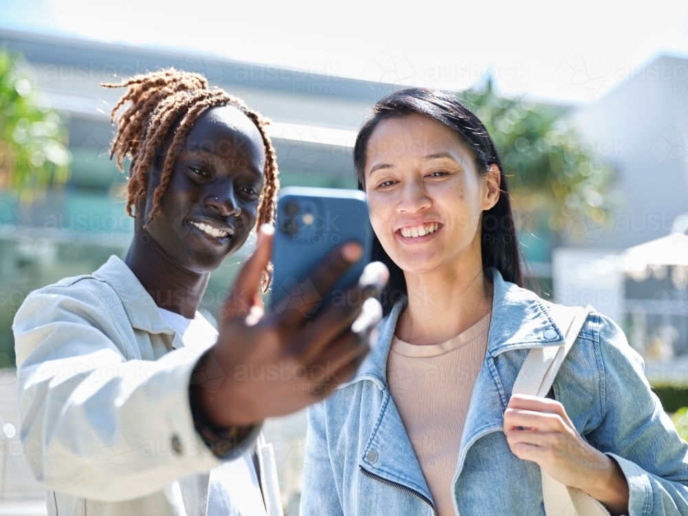 Sudanese man and Asian woman taking a selfie outside - Australian Stock Image