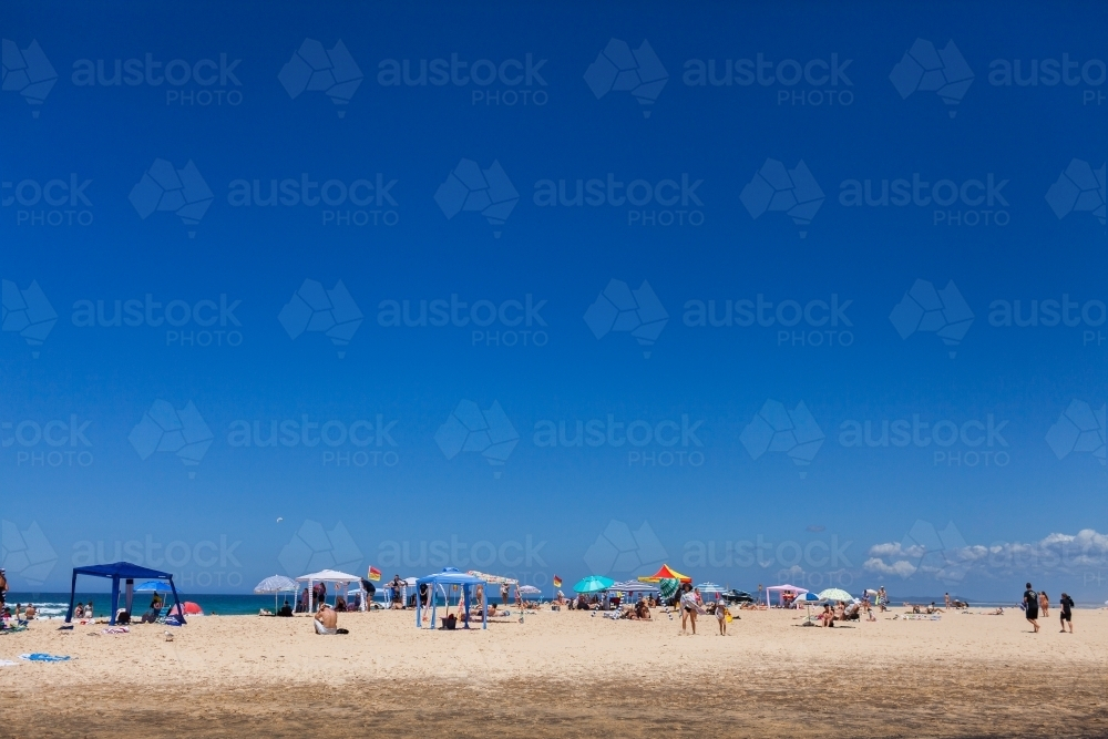 Summer day beach scene with blue sky and tents for shade - Australian Stock Image