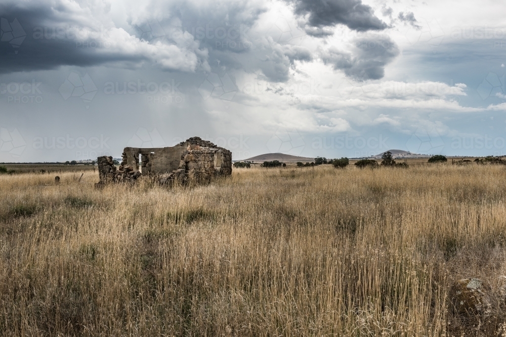 Summer storm over tumble down stone house - Australian Stock Image