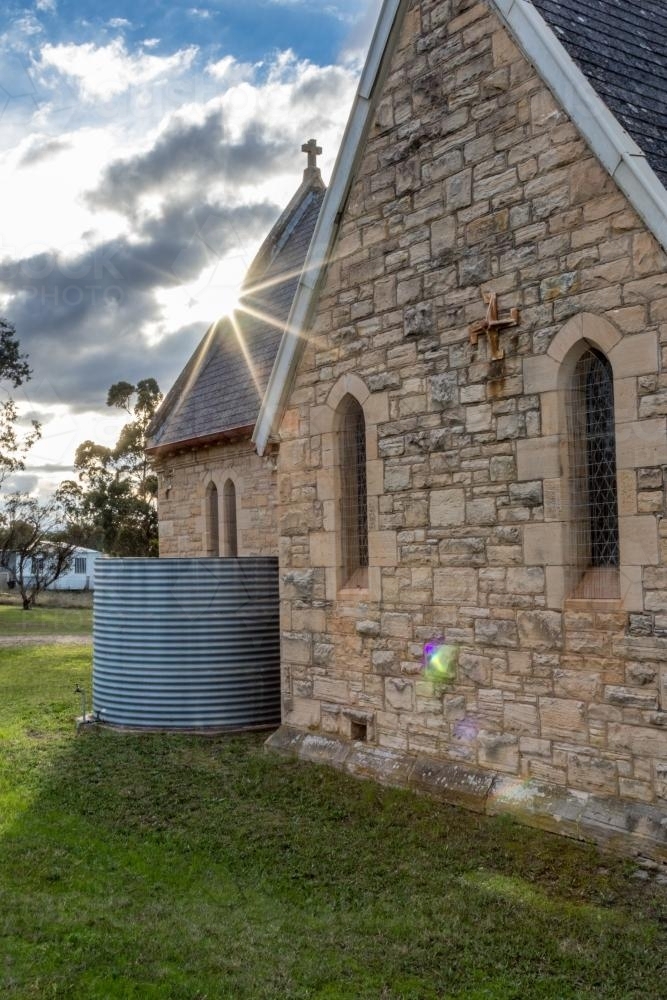 Sun bursting through clouds over country Church at Jerry's Plains - Australian Stock Image