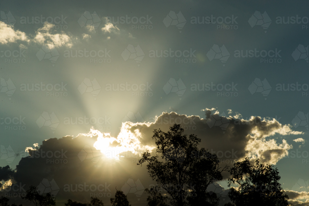Sun bursts through thick clouds sending radiant beams - Australian Stock Image