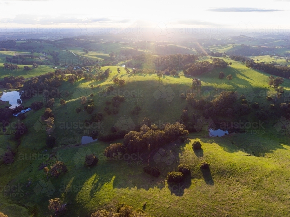 sun flare on the horizon of landscape overlooking verdant countryside - Australian Stock Image