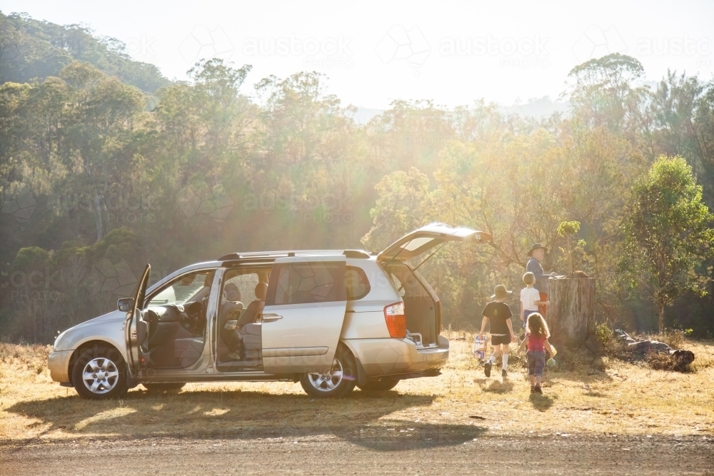 Sun flare over family car stopped beside rural road dad and children beside vehicle - Australian Stock Image