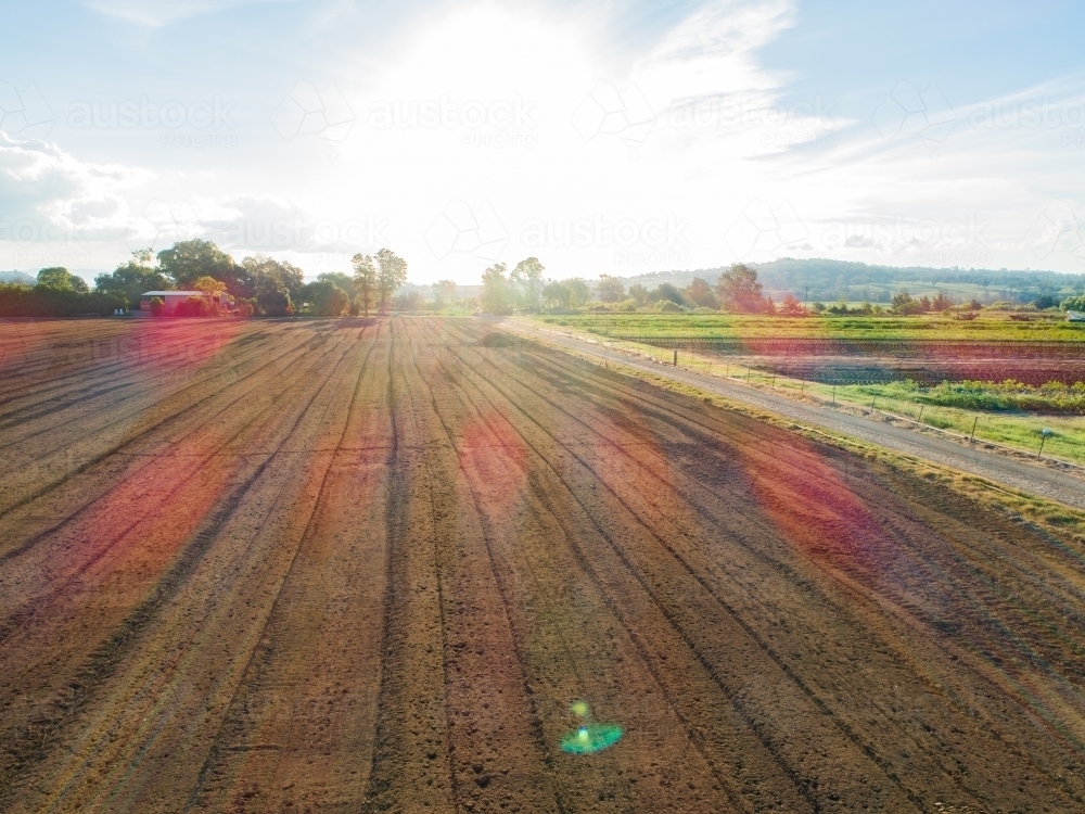 Sun flare over farm paddock with soil ready for planting - Australian Stock Image