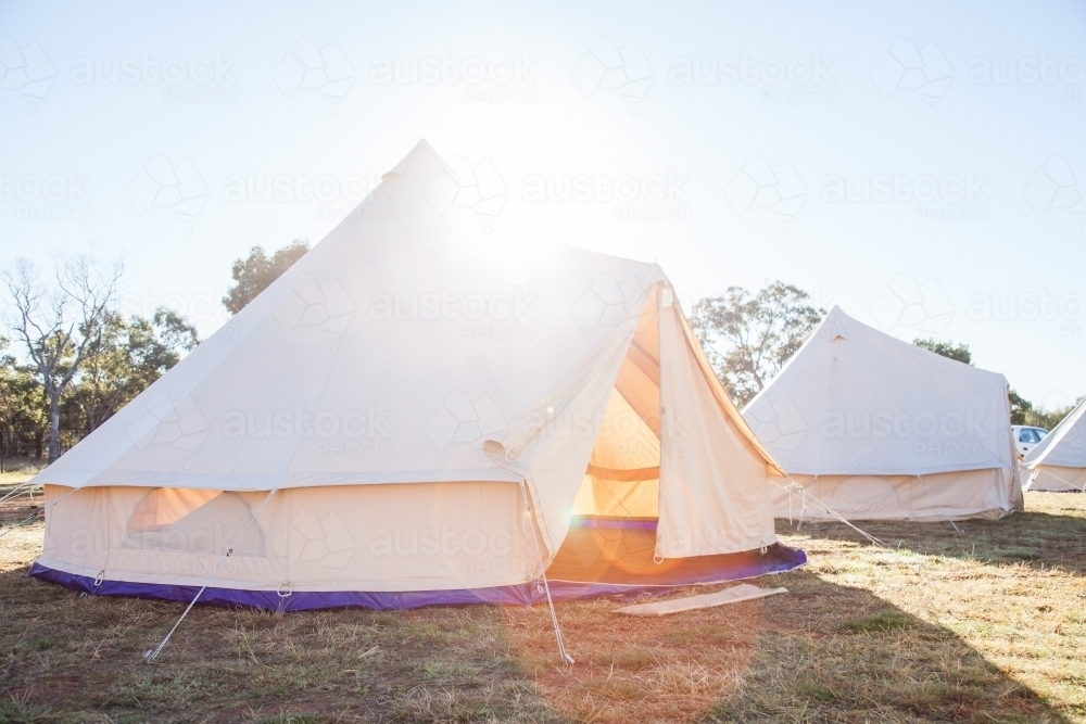 Sun flare over huge white tent with open flaps in the morning - Australian Stock Image