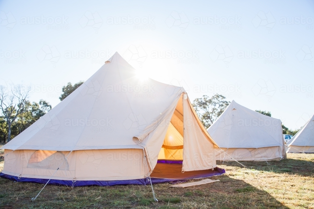 Sun flare over old fasioned white tent with open flaps in the morning - Australian Stock Image