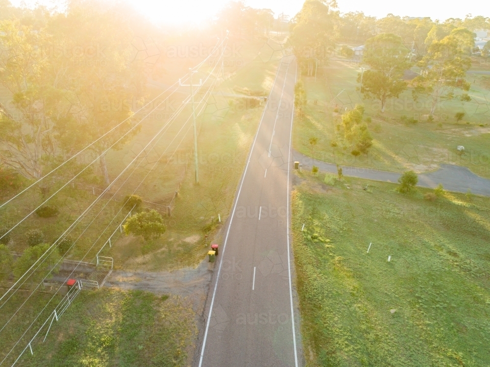 Image of Sun flare over rural road and recycling bins - Austockphoto