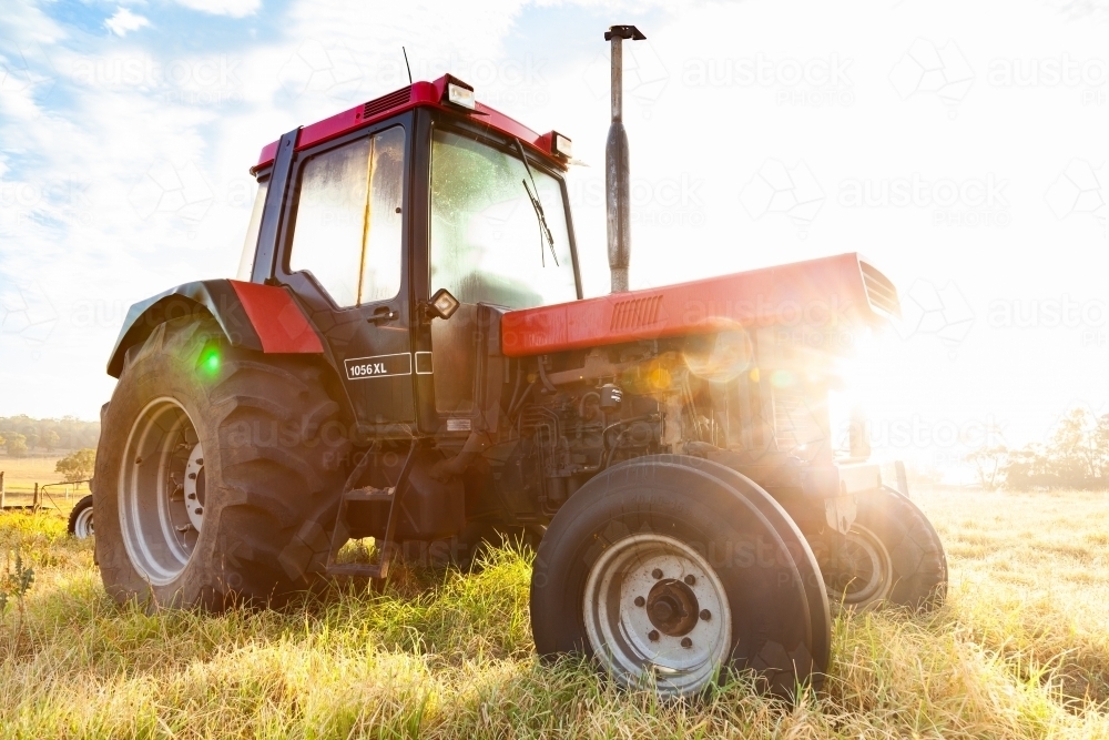 Sun flare through tractor in paddock on farm - Australian Stock Image