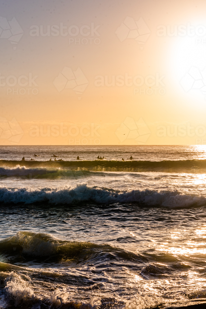 Sun Glare Over Breaking Waves and surfers - Australian Stock Image
