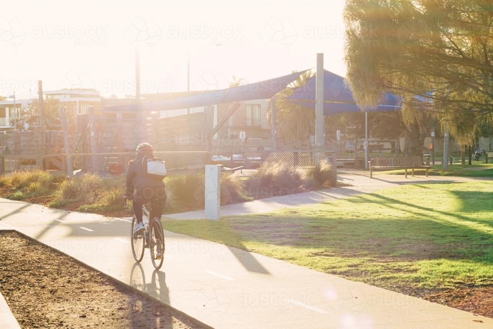 Sun haze over cyclist riding on a bike path in Brighton - Australian Stock Image
