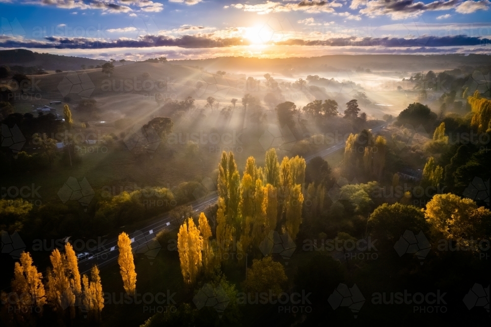 Sun ray beams covering the countryside as the fog covers the land - Australian Stock Image