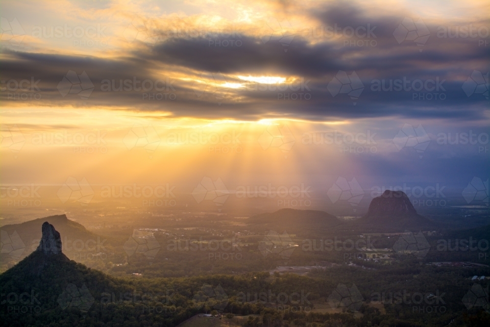 Sun rays coming through the clouds high up in the glass house mountains - Australian Stock Image