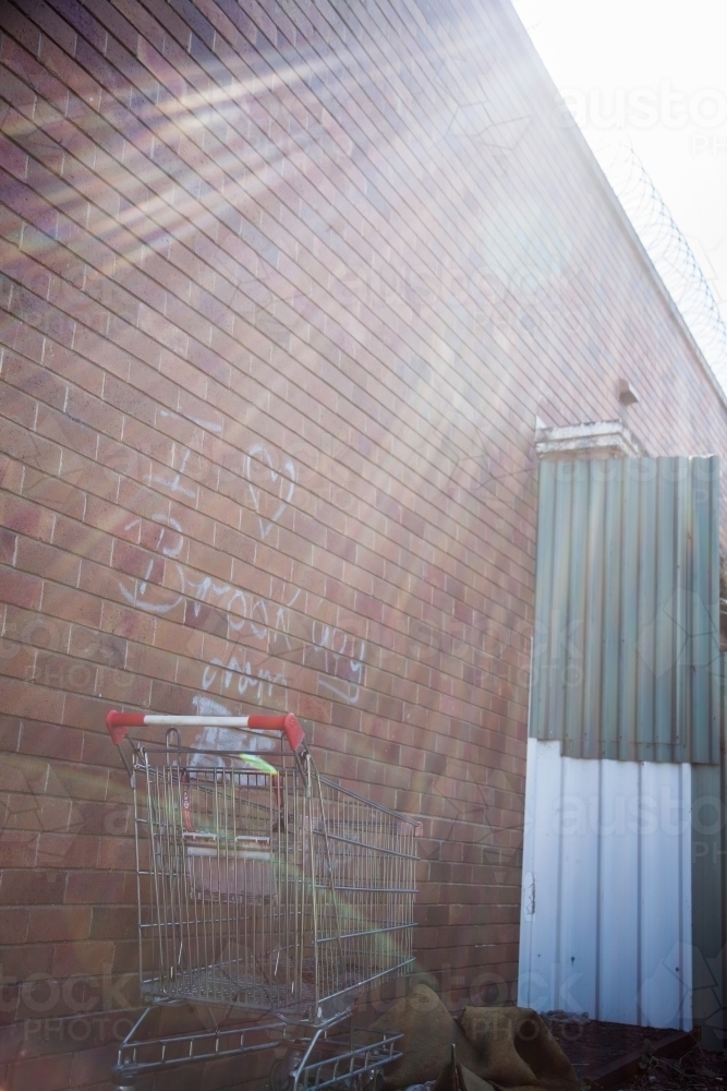 Sun rays on a lost shopping trolley in an alleyway - Australian Stock Image