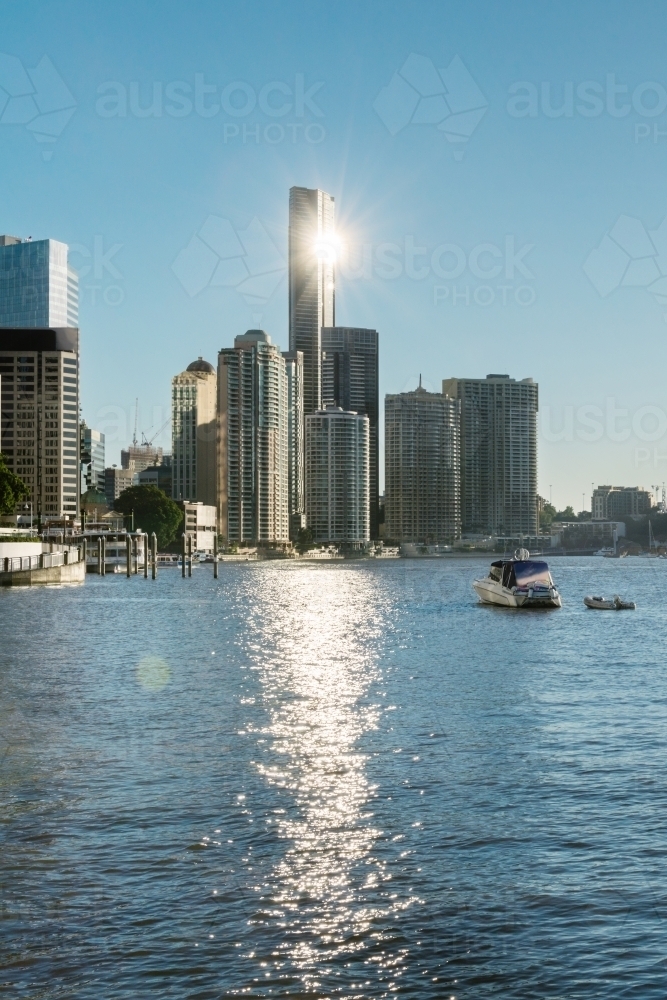 sun reflecting off tall city building over water - Australian Stock Image