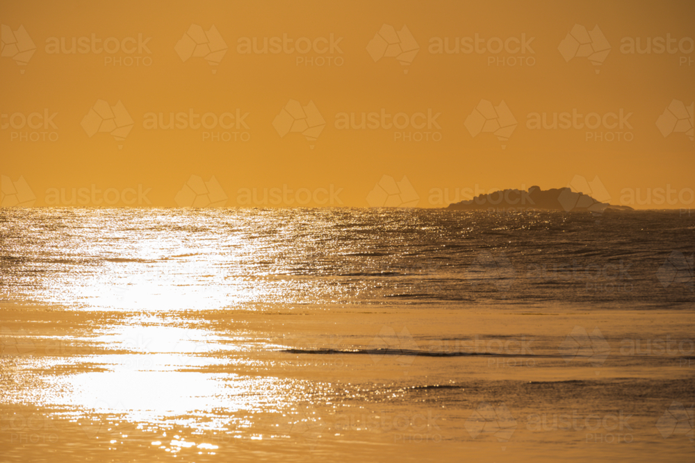 Image of Sun reflecting off the ocean and distant island during a ...