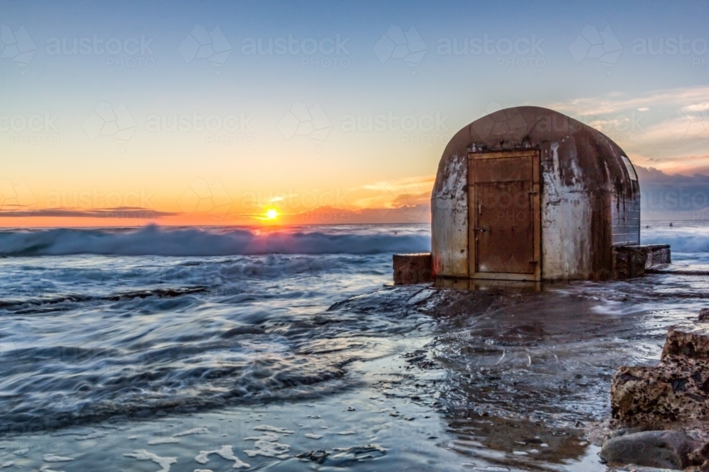 Sun rising over ocean baths pump house and coastline - Australian Stock Image