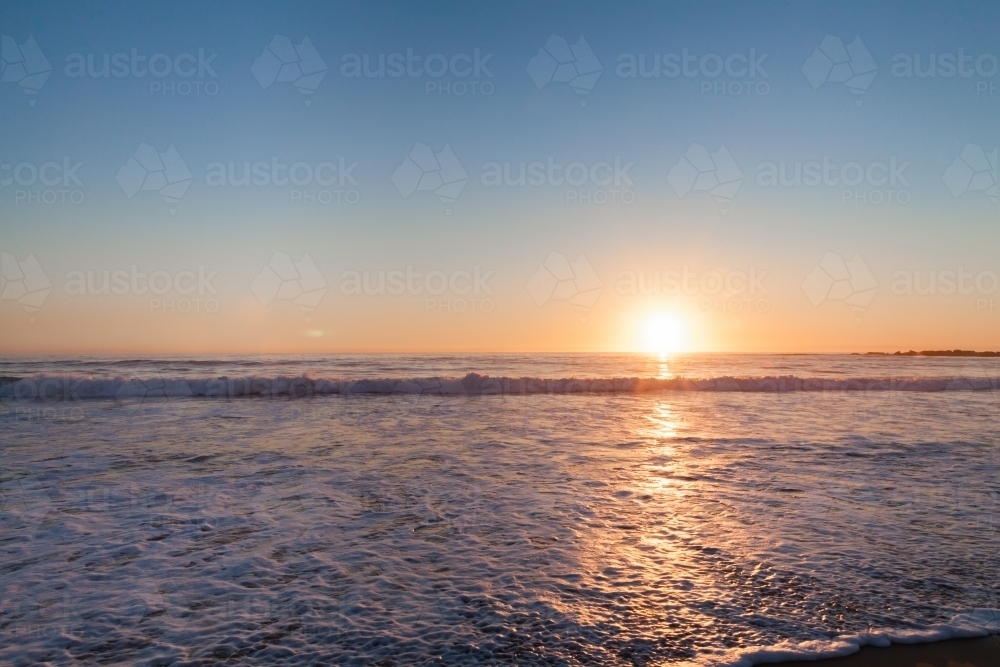 Image of Sun rising over the ocean with line of light sparkling on ...