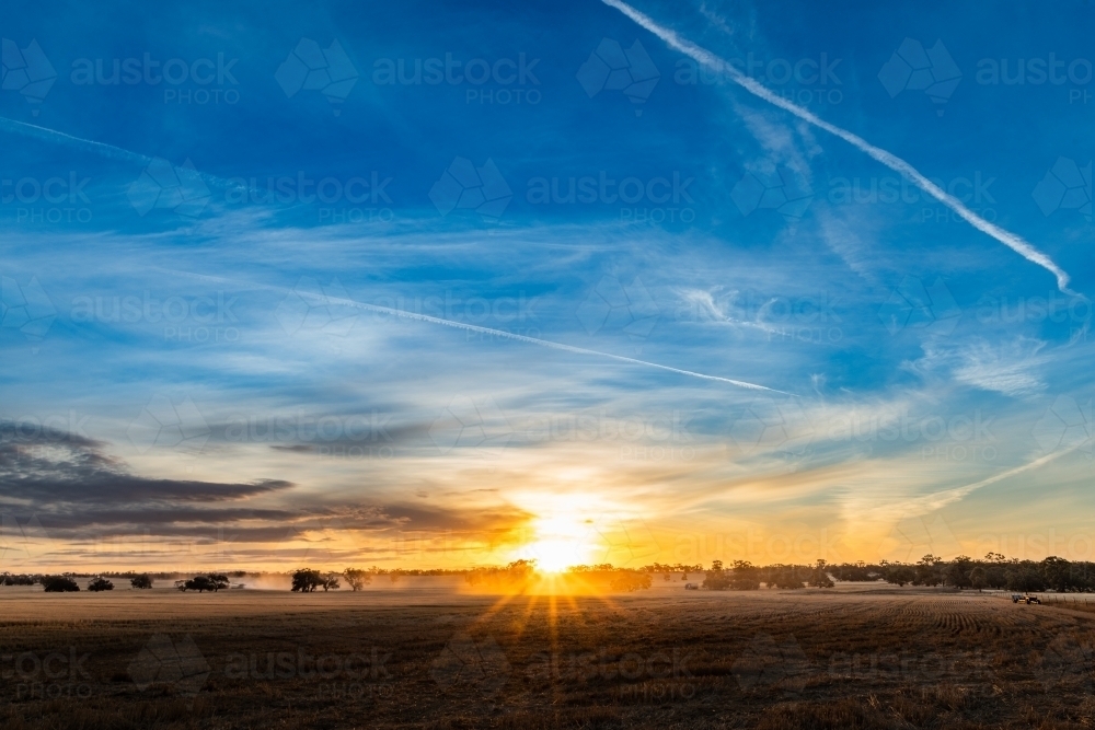 Sun sets over the open paddock land during harvesting season. - Australian Stock Image